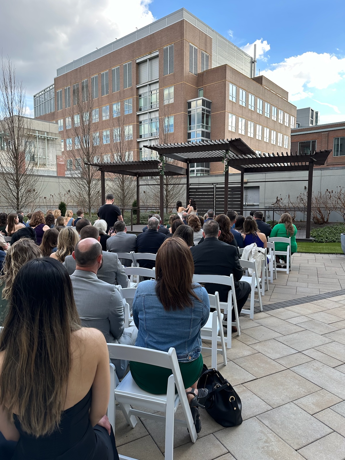 Outdoor rooftop ceremony with guests seated under a modern pergola chuppah
